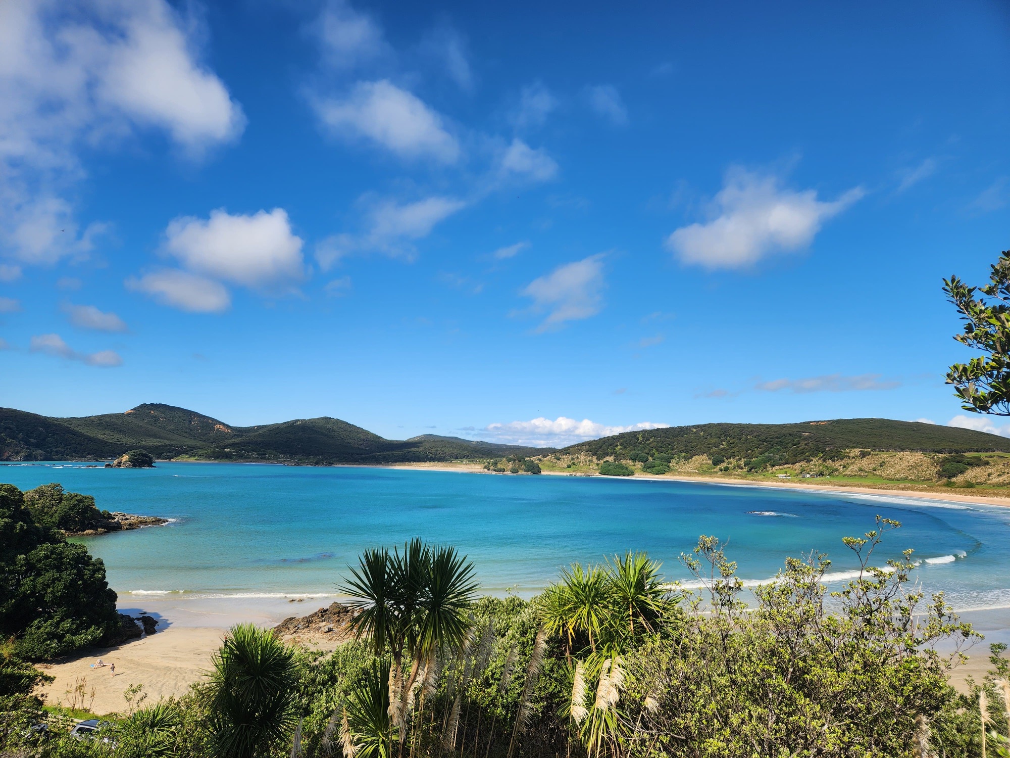 A calm turquoise bay under a clear sky, with a still horizon line.